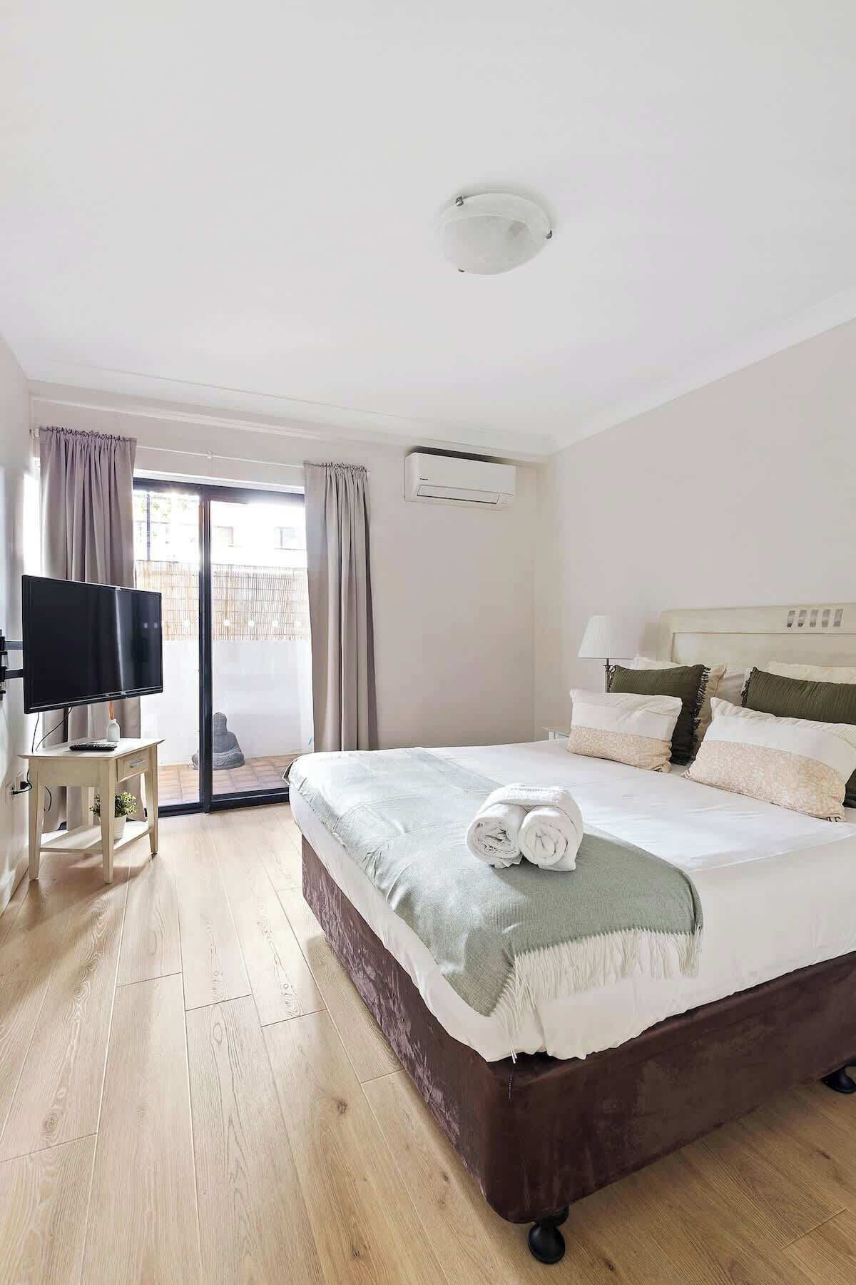A hotel room with a bed, a TV, and a sliding glass door to the outside.