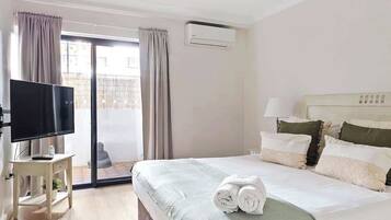 A hotel room with a bed, a TV, and a sliding glass door to the outside.