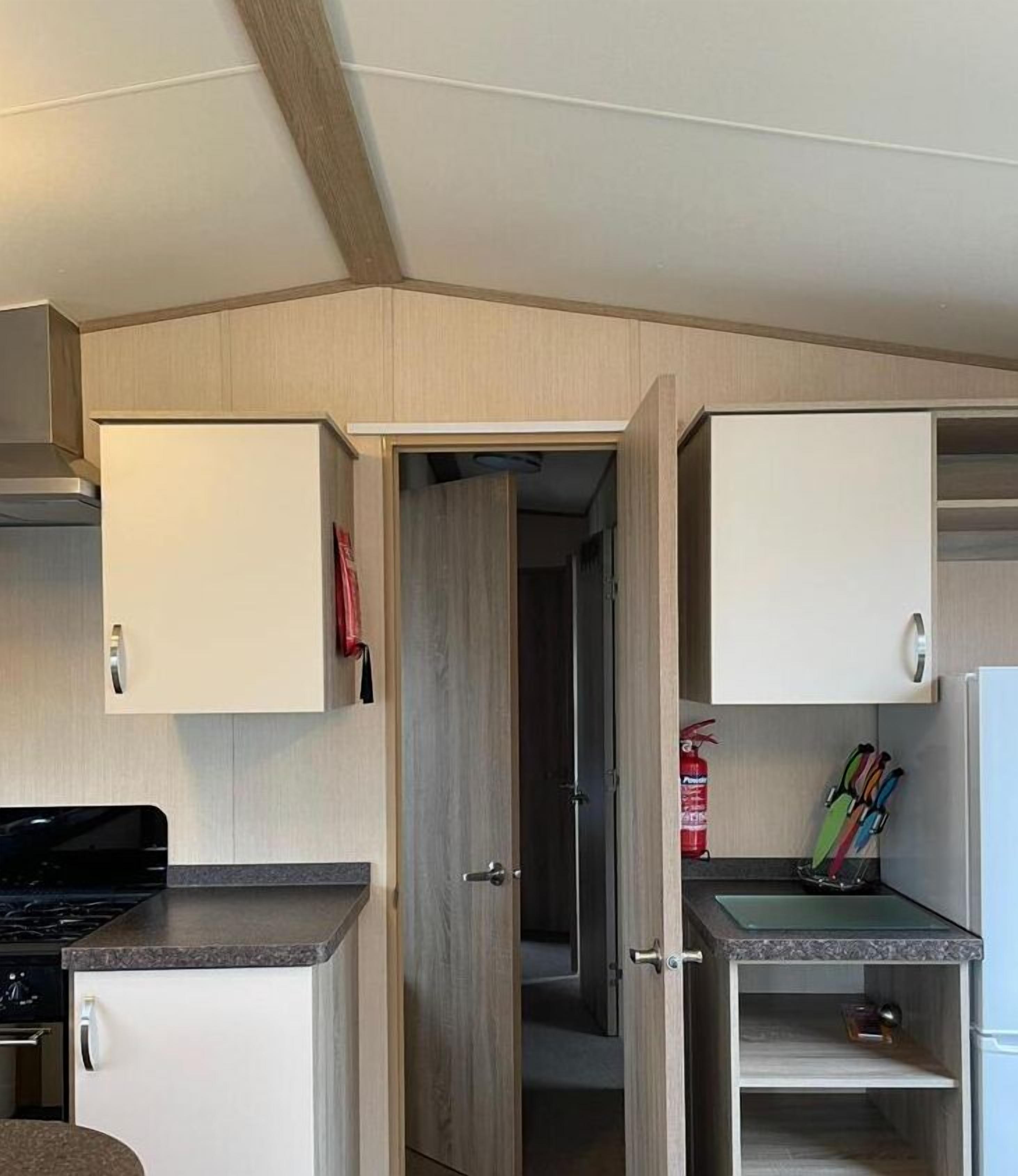 A compact kitchen with white cabinets, a stove, and a small countertop.