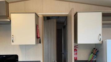 A compact kitchen with white cabinets, a stove, and a small countertop.