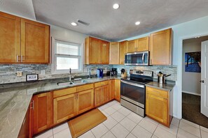 A kitchen with wooden cabinets, a stainless steel microwave, and a built-in oven. - Some Beach | Oceanfront + Direct Beach Access! (Surf City)