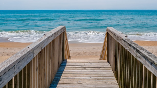 A wooden boardwalk leading to a beach with clear blue water and a sandy shore. - Some Beach | Oceanfront + Direct Beach Access! (Surf City)
