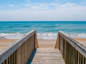 A wooden boardwalk leading to a beach with clear blue water and a sandy shore. - Some Beach | Oceanfront + Direct Beach Access! (Surf City)