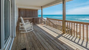 A wooden deck with a railing overlooking the ocean, a rocking chair, and a view of the beach. - Some Beach | Oceanfront + Direct Beach Access! (Surf City)