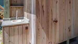 A wooden outdoor shower with a stone sink and a metal faucet. - Some Beach | Oceanfront + Direct Beach Access! (Surf City)