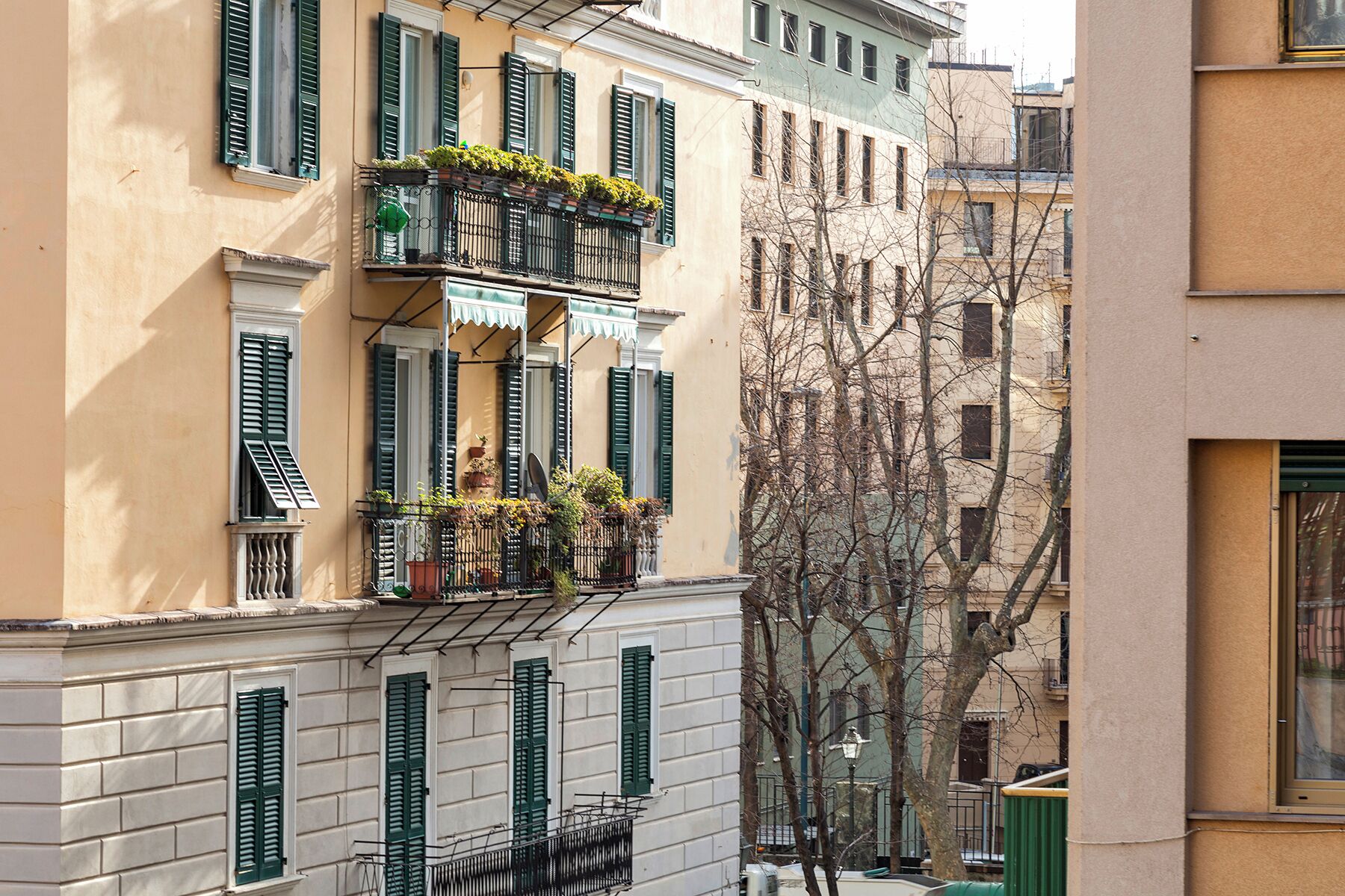 A multi-story building with balconies, some with plants.