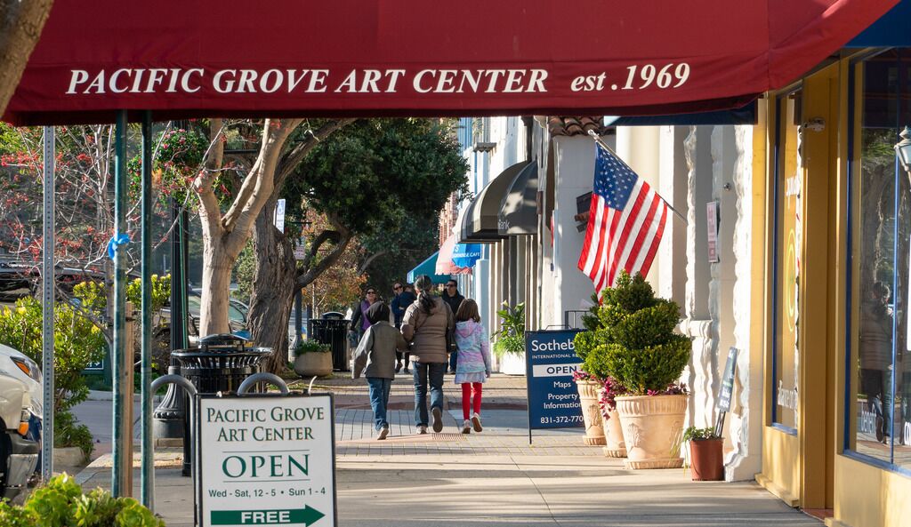 The Pacific Grove Art Center with an American flag and a sign indicating it's open.