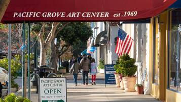 The Pacific Grove Art Center with an American flag and a sign indicating it's open.