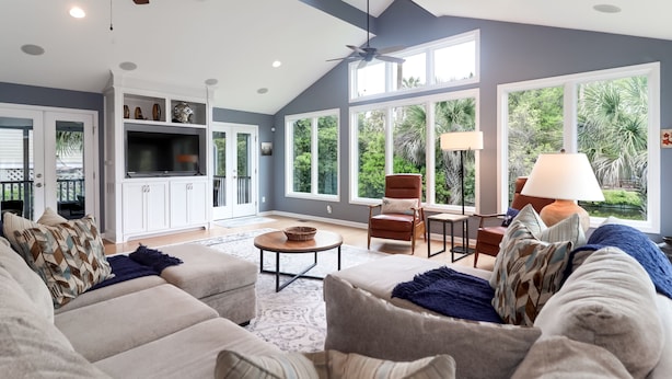 A spacious living room with a high ceiling, large windows, and a ceiling fan. - Coastal family friendly home, Lagoon View, walkable to beach - 25 Fairway Oaks (Isle of Palms)