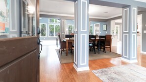 A spacious dining area with a large table and chairs, a wooden floor, and a view of the outdoors. - Coastal family friendly home, Lagoon View, walkable to beach - 25 Fairway Oaks (Isle of Palms)