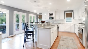A spacious kitchen with white cabinets, a large island, and modern appliances. - Coastal family friendly home, Lagoon View, walkable to beach - 25 Fairway Oaks (Isle of Palms)