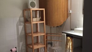 Een badkamer met een toilet, een houten kastje, een witte wastafel en een douchehoek.