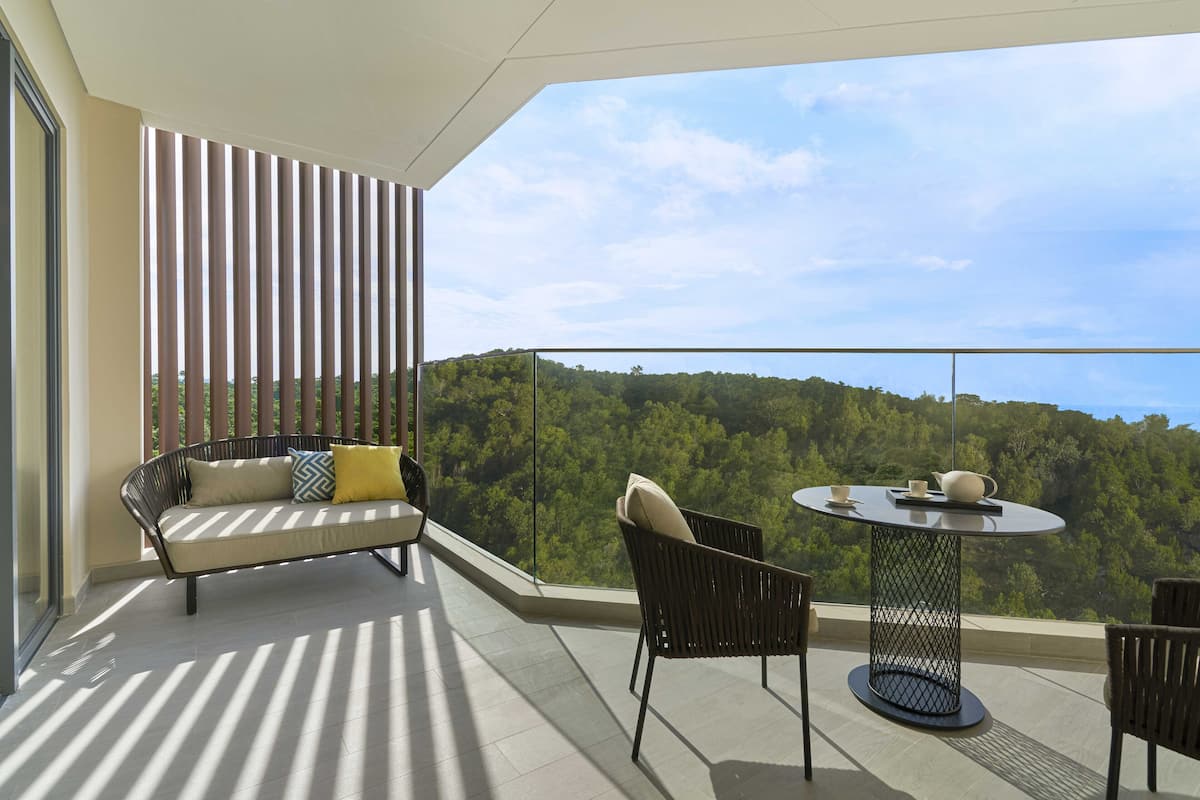 Een balkon met een bank, stoelen en een tafel.