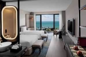 Habitación de hotel con una cama grande, un escritorio, un televisor y vista al océano.