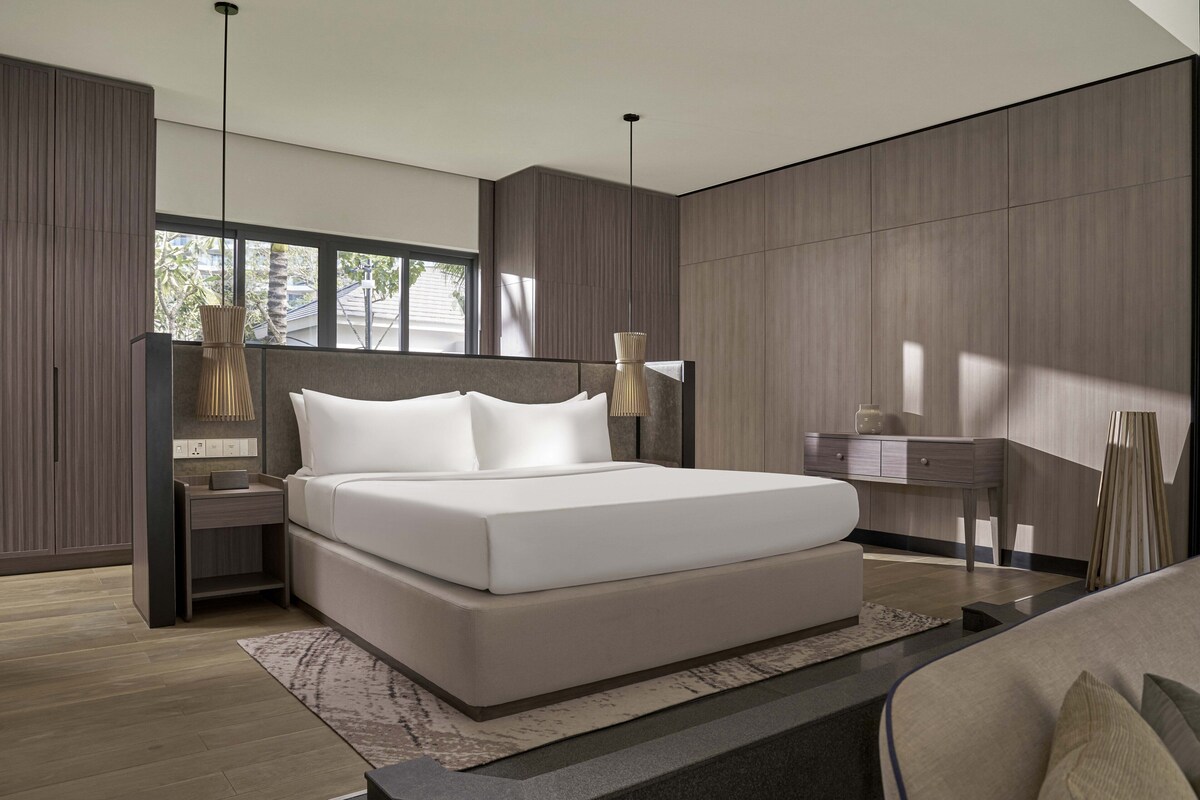 Une chambre à coucher moderne avec un grand lit, des tables de chevet, une commode et un bureau avec une lampe.