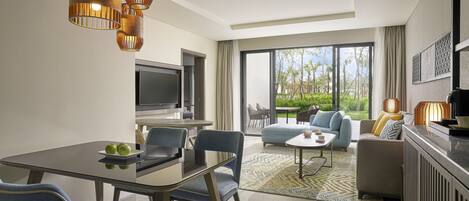 A modern living room with a dining area, large windows, and a view of greenery.