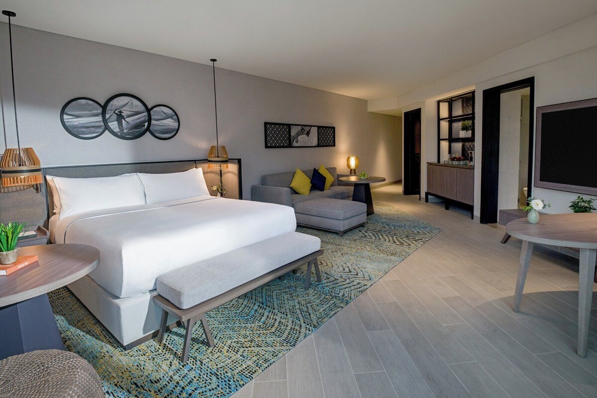 Een moderne hotelkamer met een groot bed, een bank, een bijzettafeltje en een televisie.