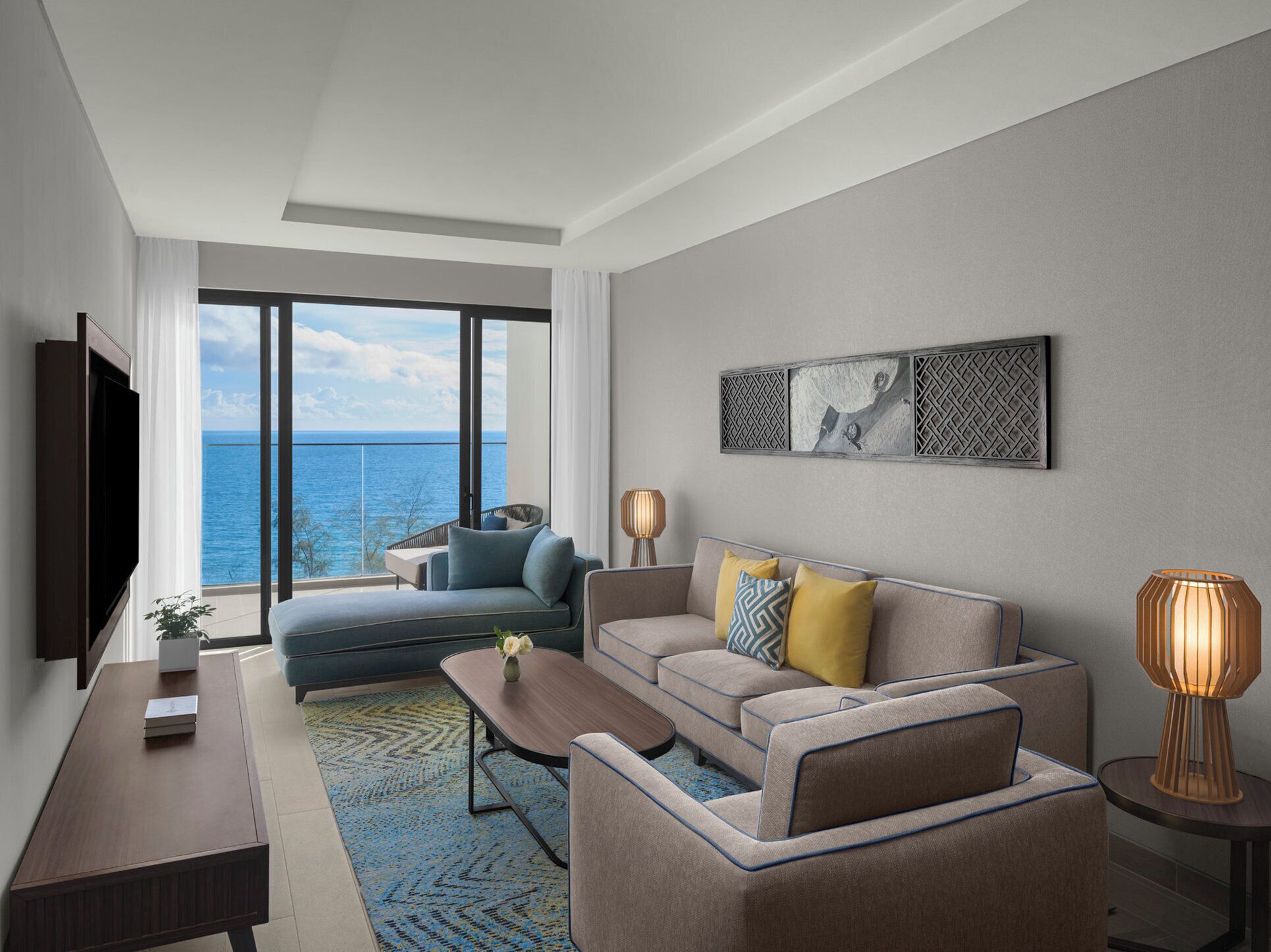 A modern living room with a sofa, coffee table, and TV, overlooking a scenic ocean view.