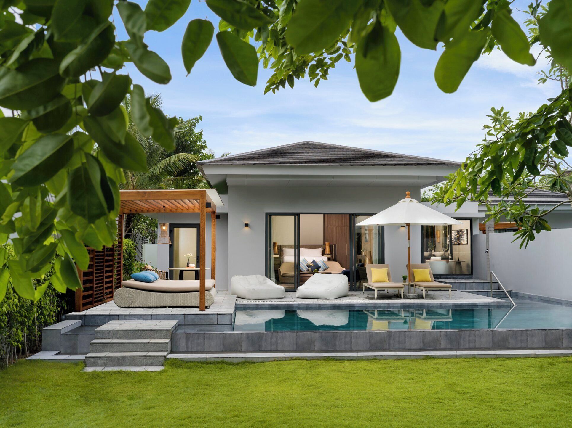 A modern house with a swimming pool, outdoor seating, and a covered patio area.