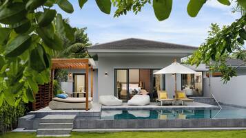 A modern house with a swimming pool, outdoor seating, and a covered patio area.