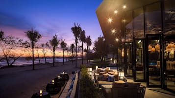 A beachfront property with outdoor seating and a view of the ocean at dusk.