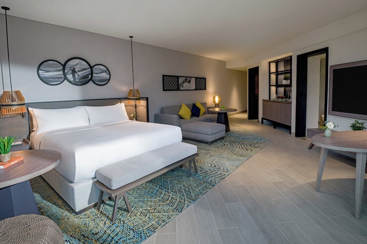 Een moderne hotelkamer met een groot bed, een bank, een bijzettafeltje en een televisie.