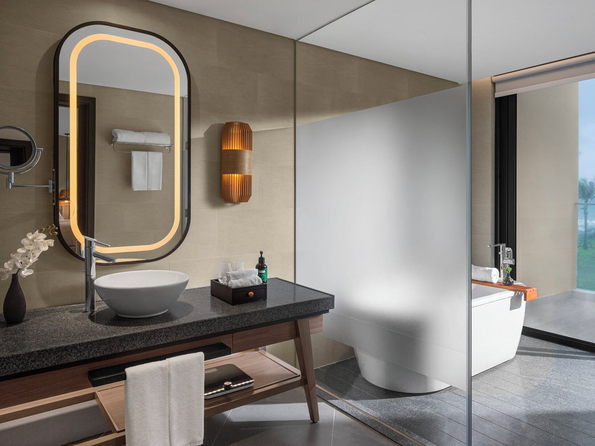Une salle de bain moderne avec un grand miroir, un lavabo blanc et une douche à parois de verre.