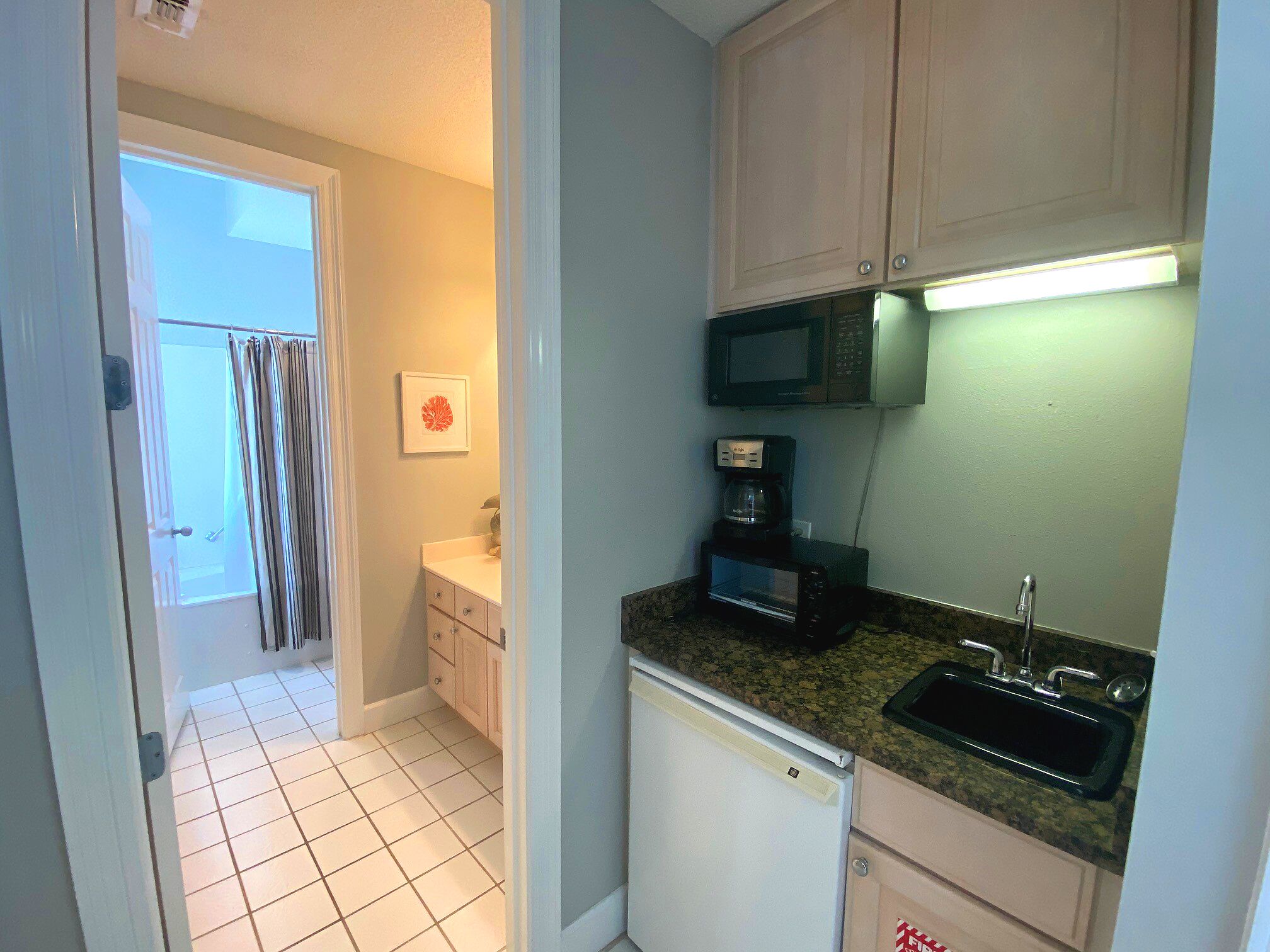 A compact kitchen with a microwave, coffee maker, and sink.