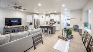 A modern kitchen with white cabinets, a central island, and bar stools. - Inviting 4BR Sleeps 12 Near Pool - Chef's Kitchen (St. George)