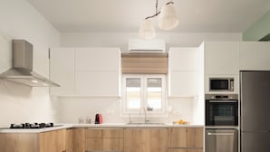Une cuisine moderne avec des meubles en bois, un réfrigérateur en acier inoxydable, un four à micro-ondes et une cuisinière à gaz.