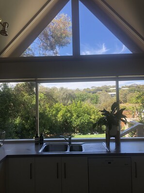 Enjoy a view of the lush landscape from the kitchen window, where a potted plant adds a touch of greenery.