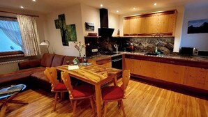 Una cocina compacta con armarios de madera, una mesa de comedor con sillas y una estufa empotrada.