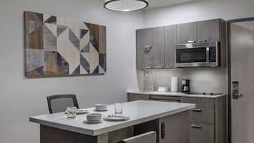 A modern kitchen with a central island, stainless steel appliances, and a geometric wall art piece.