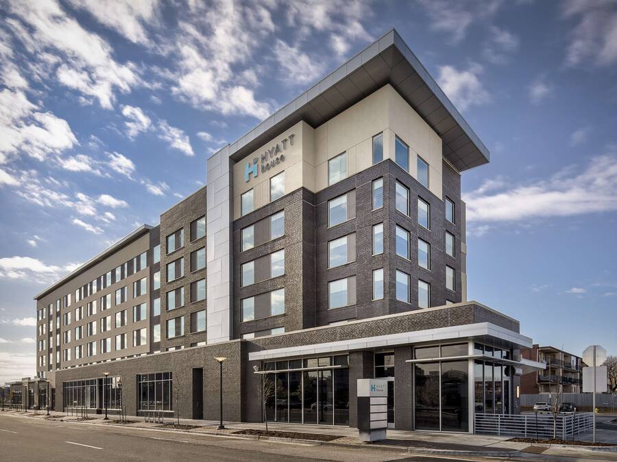 A modern hotel building with a flat roof, large windows, and a prominent sign.
