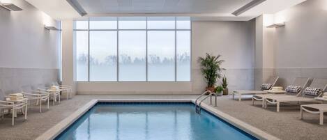 Uma piscina com espreguiçadeiras e uma janela grande.