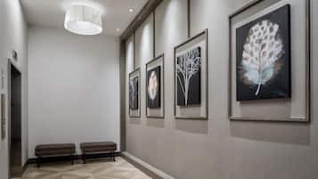Un pasillo con un banco, obras de arte enmarcadas y una lámpara moderna.