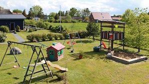 Une aire de jeux avec des balançoires, des toboggans et une petite cabane.