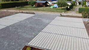Un espace extérieur aménagé avec un revêtement pavé, un parterre fleuri et une tente.