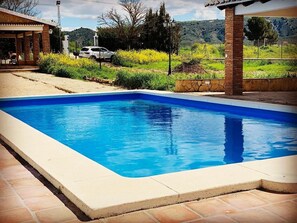 Relax by the pool surrounded by a tranquil outdoor space with a covered area and scenic views.
