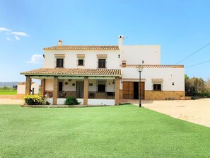 Situated in a rural setting, this traditional home offers a covered patio area with seating for relaxation and social gatherings.