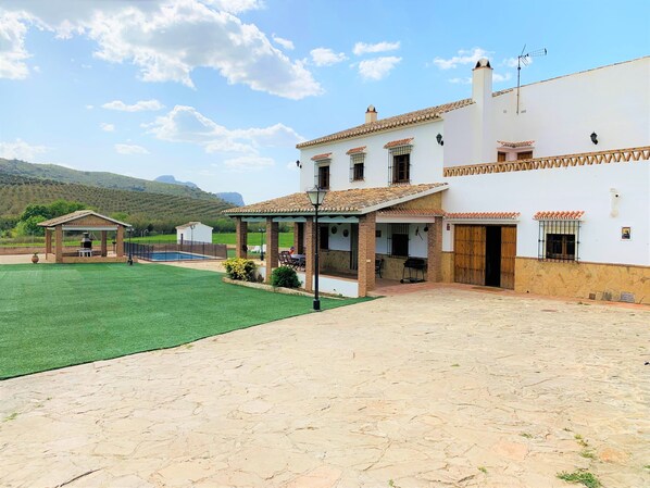 Relax in a spacious outdoor area with a well-maintained lawn and pool, featuring a covered patio with seating for outdoor dining or relaxation.