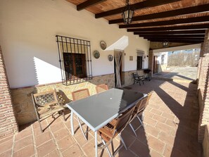 Relax in the serene outdoor patio surrounded by a glass-top table and comfortable chairs.
