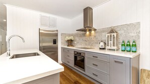 A modern kitchen with a stainless steel refrigerator, a built-in oven, and a sink with a faucet. - Sea Deck, Hyams Beach, Jervis Bay (Hyams Beach)