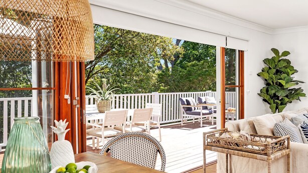 A spacious outdoor deck with white railings, wicker furniture, and a view of lush greenery. - Sea Deck, Hyams Beach, Jervis Bay (Hyams Beach)