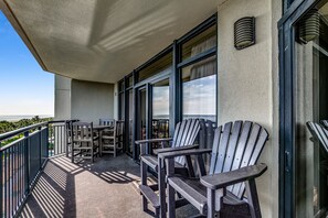 Un balcon avec des fauteuils Adirondack, une table et une vue sur l’océan.