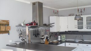 A modern kitchen with white cabinets, a stainless steel island, and bar stools. - Gites de Daumesnil 5 minutes walk from town center. (Morlaix)