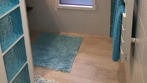 A small bathroom with a frosted window, a blue rug, and a towel rack.
