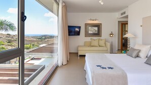Una habitación de hotel con balcón, cama, sofá y escritorio.