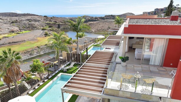 Zona de piscina en la azotea con vistas al paisaje circundante, que incluye un cuerpo de agua y colinas.