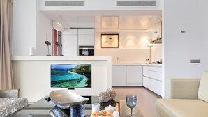 Una sala moderna con televisor, mesa de comedor con desayuno servido y un sofá.